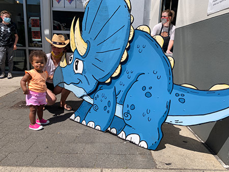 Toddler and mom standing next to Albertasaurus on Alberta Street.